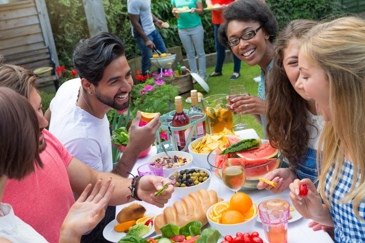Friends sharing a summer cookout meal at an outdoor table