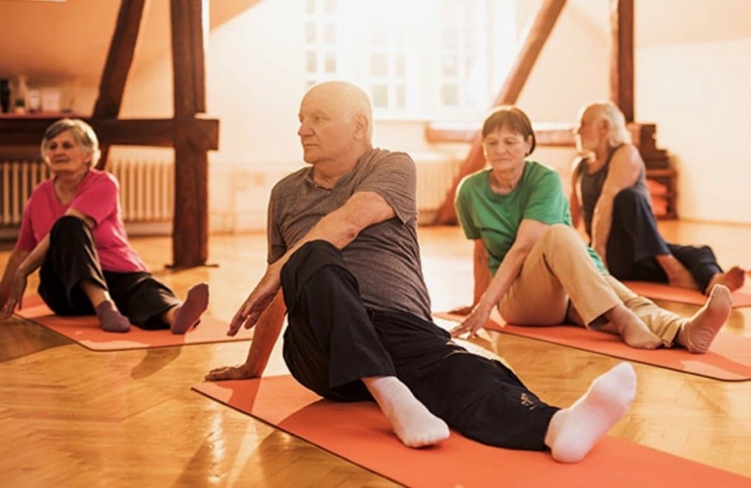 Older adults stretching on mats in an exercise class