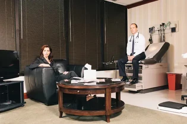 Physician seated on an exam table across from a woman in an office