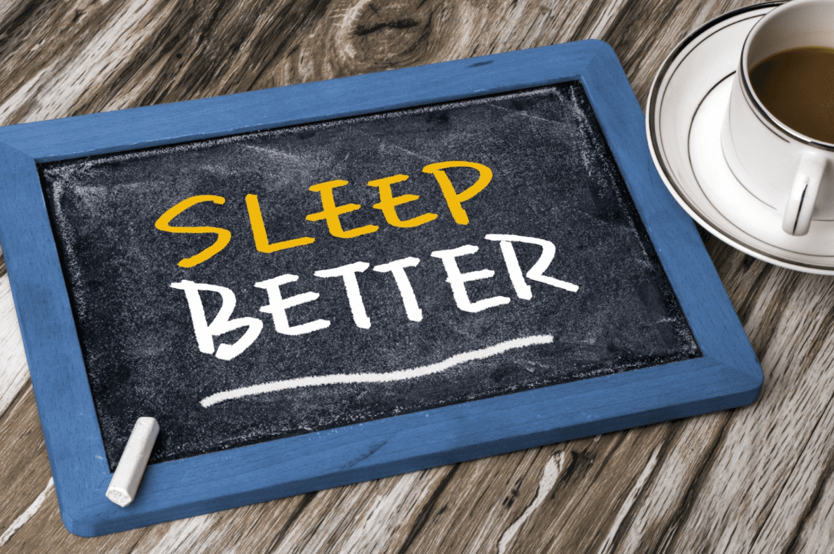 Chalkboard reading Sleep Better beside a cup of coffee