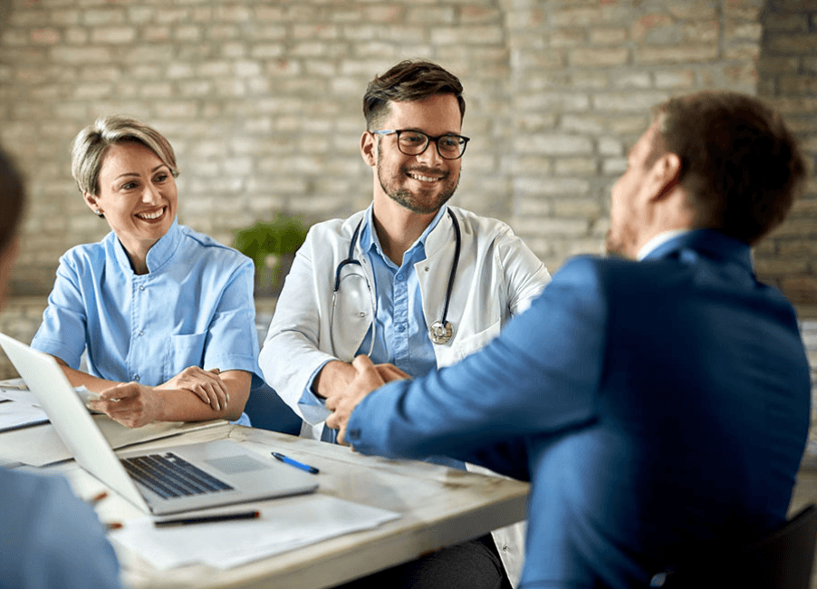 Physician and nurse meeting with a man at an office table